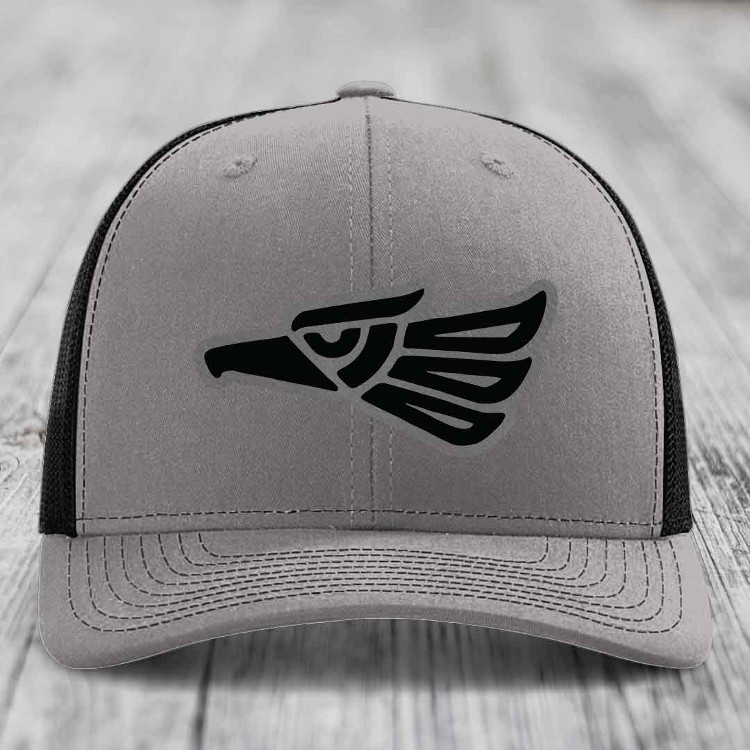 Grey trucker hat with black Aztec-style eagle patch on front.