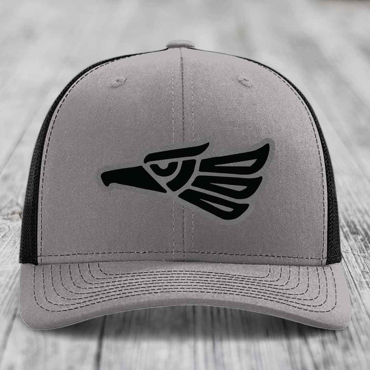 Grey trucker hat with black Aztec-style eagle patch on front.