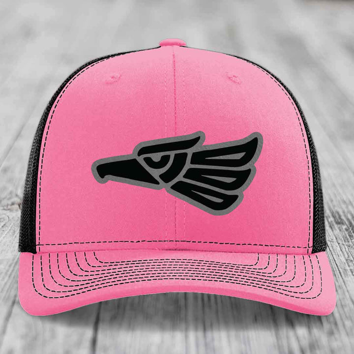 Pink trucker hat with black and grey eagle patch on front, black mesh back.