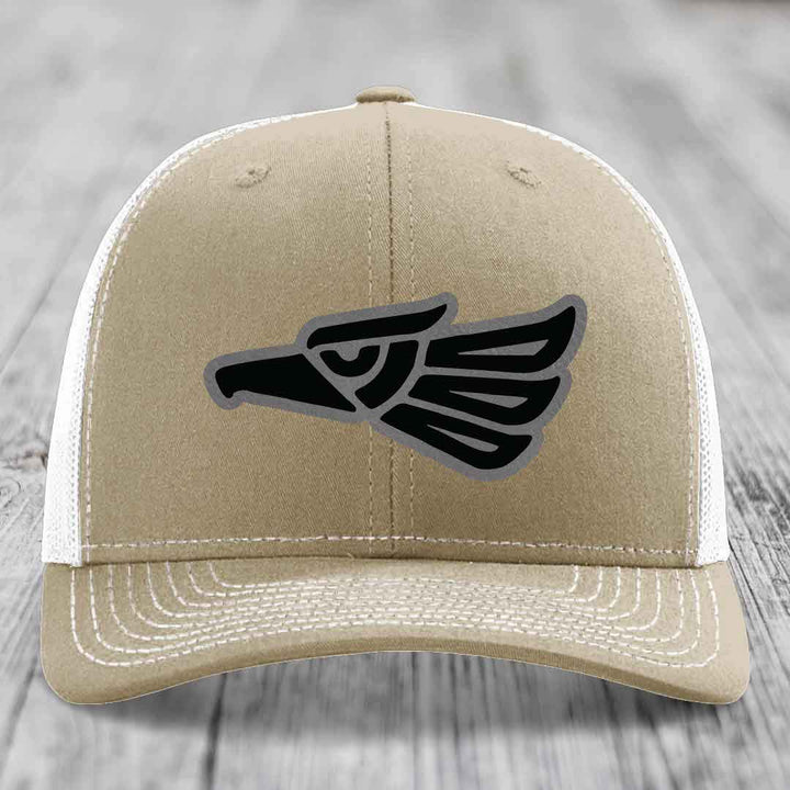 Tan trucker hat with black and grey Aztec eagle patch on front.