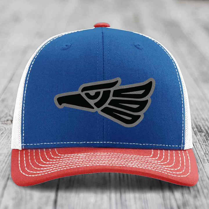 Blue and red trucker hat with embroidered eagle patch on front, white stitching, and red button.