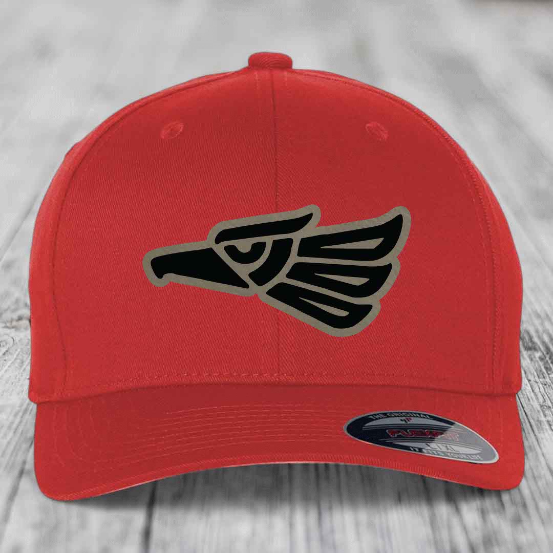 Red baseball cap with black and grey Aztec eagle patch on front, Flexfit brand label visible.