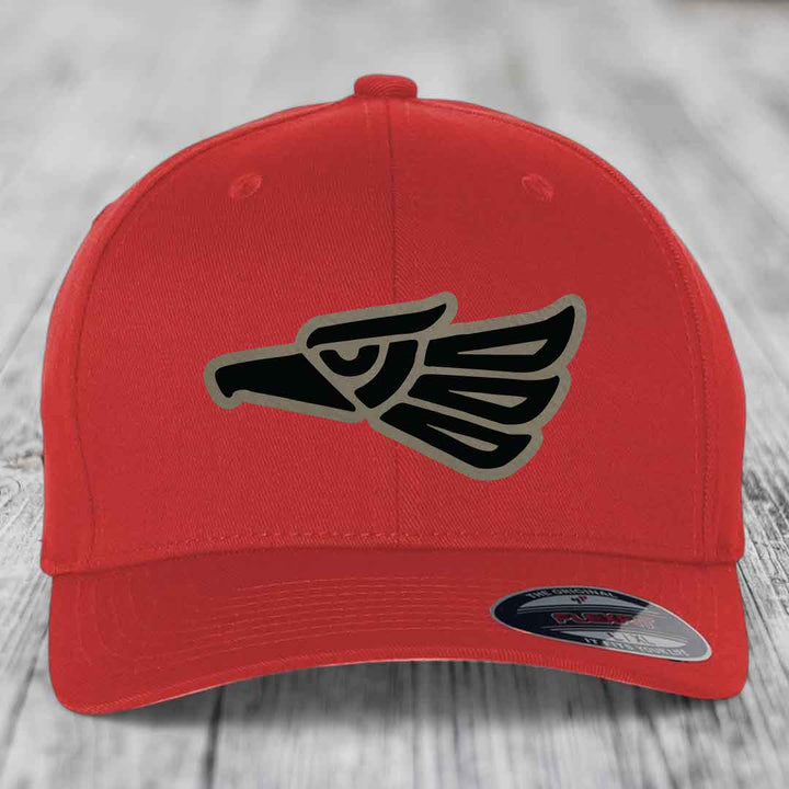 Red baseball cap with black and grey Aztec eagle patch on front, Flexfit brand label visible.