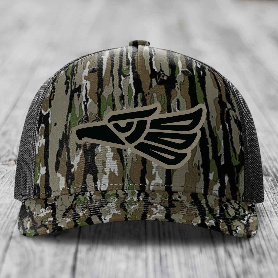 Camouflage trucker hat with black eagle patch on front, gray mesh back.