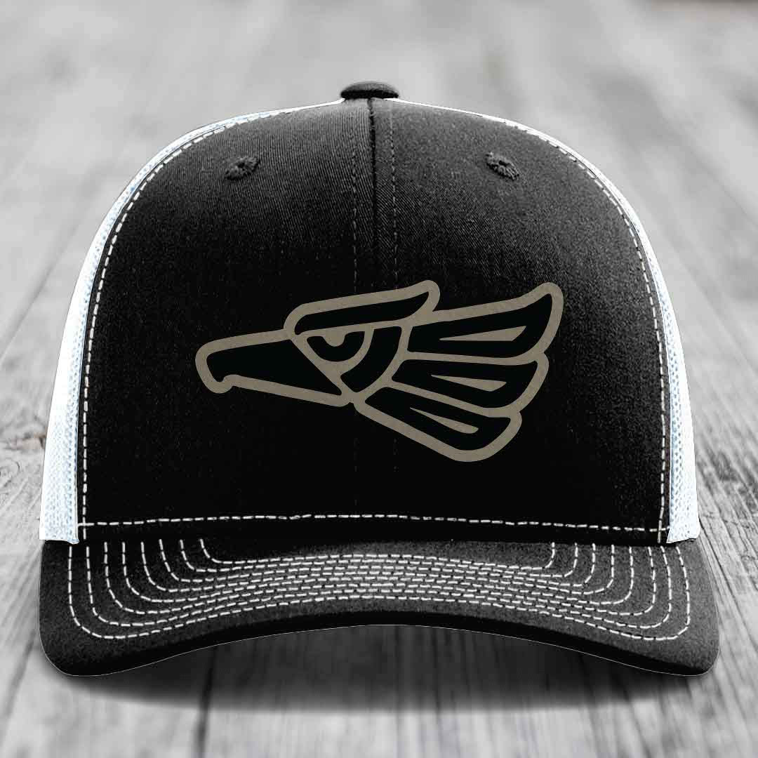 Black trucker hat with white mesh back and stitching, featuring a grey eagle head patch on front.