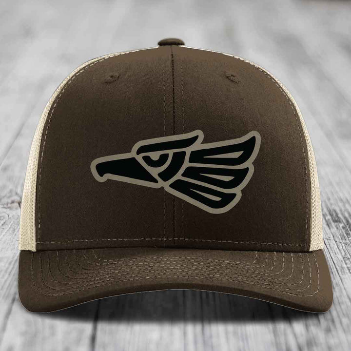 Brown trucker hat with black and tan eagle patch on front, white mesh back.