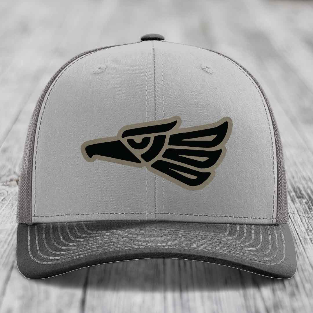 Grey trucker hat with black and tan Aztec eagle patch on front.