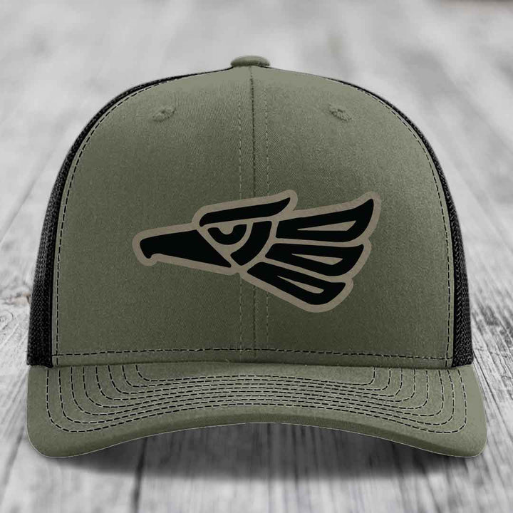 Olive green trucker hat with black and tan Aztec eagle patch on front.