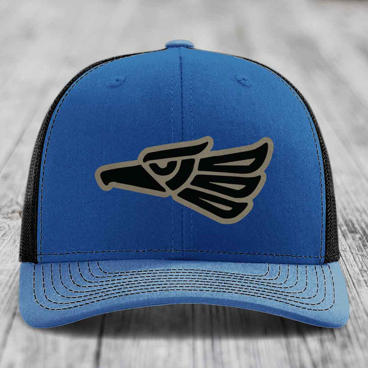 Blue trucker hat with black and tan eagle patch on front, black mesh back.