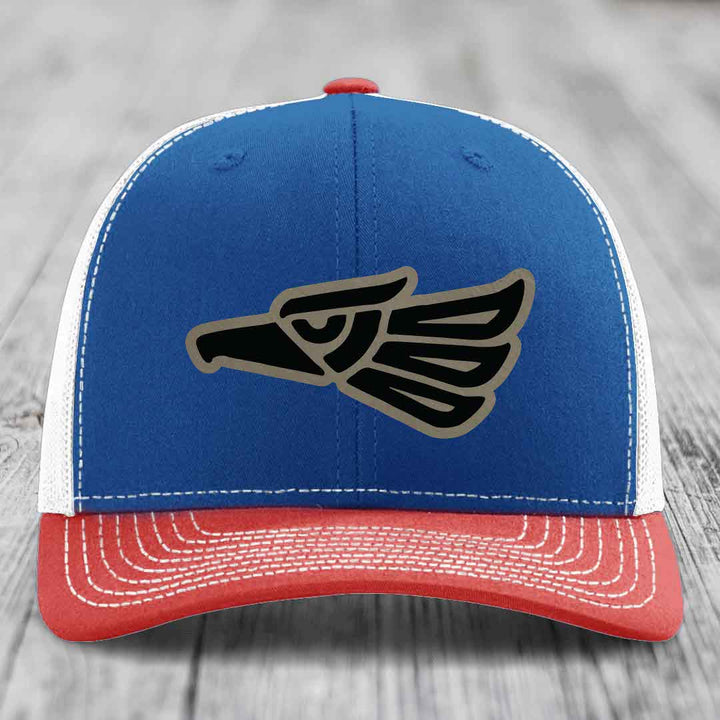 Blue and red trucker hat with black and grey Aztec eagle patch on front.