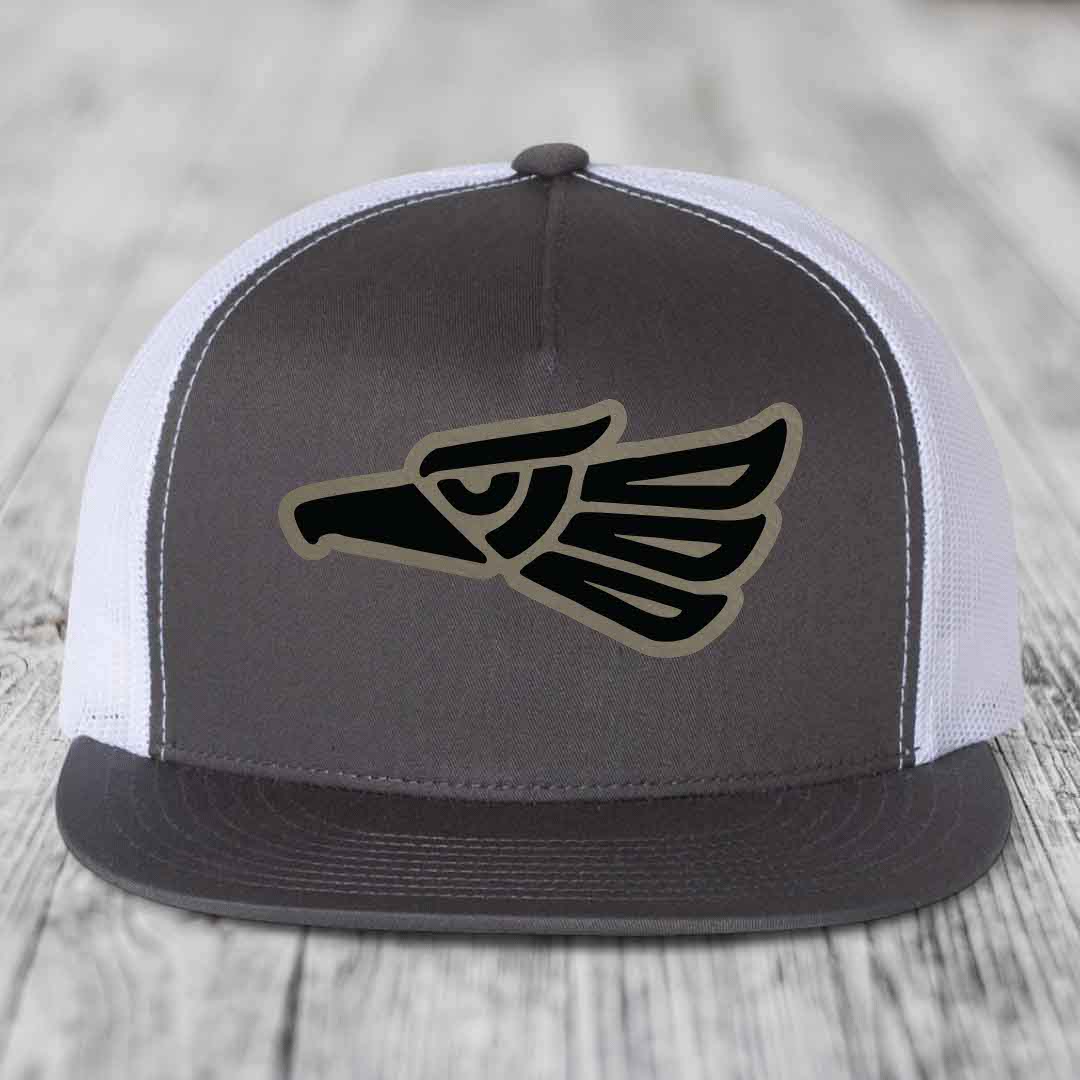 Grey front panel trucker hat with black and tan Aztec eagle patch, white mesh back, and grey brim.