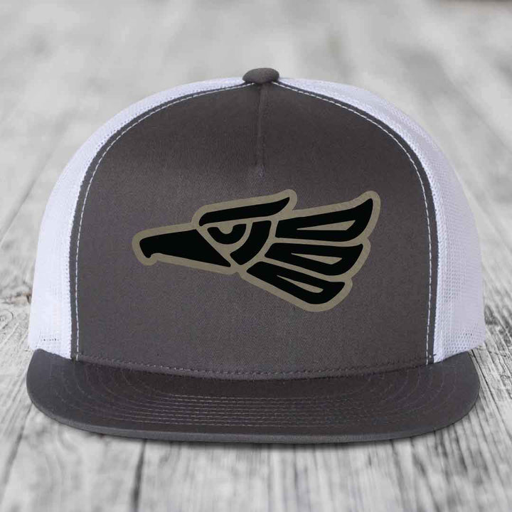 Grey front panel trucker hat with black and tan Aztec eagle patch, white mesh back, and grey brim.