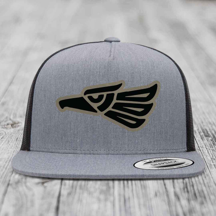 Grey trucker hat with black and tan Aztec eagle patch on front.