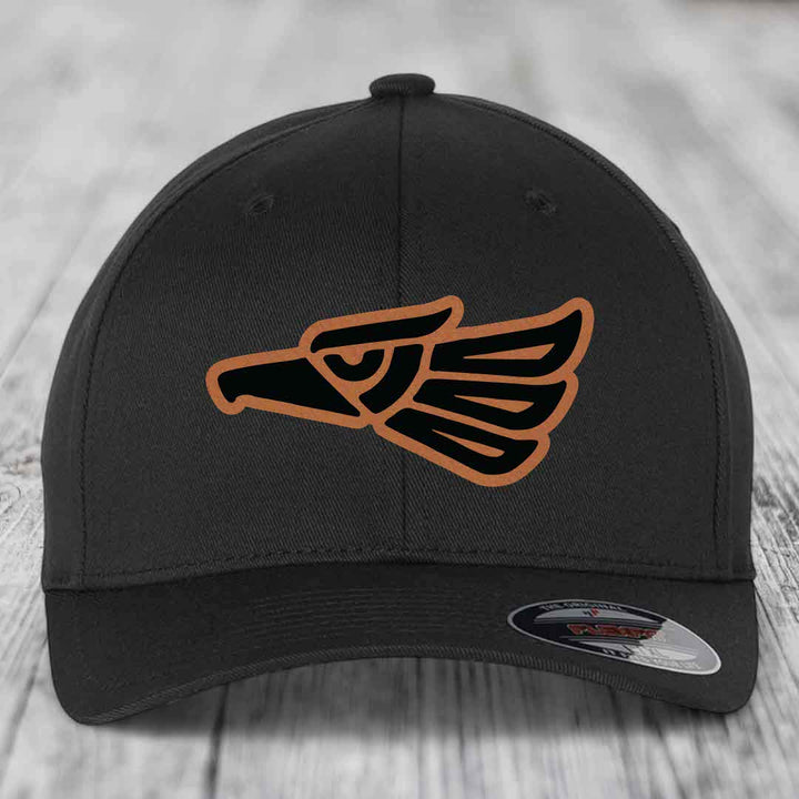 Black baseball cap with Aztec-style eagle patch in black and tan, featuring a Flexfit label.