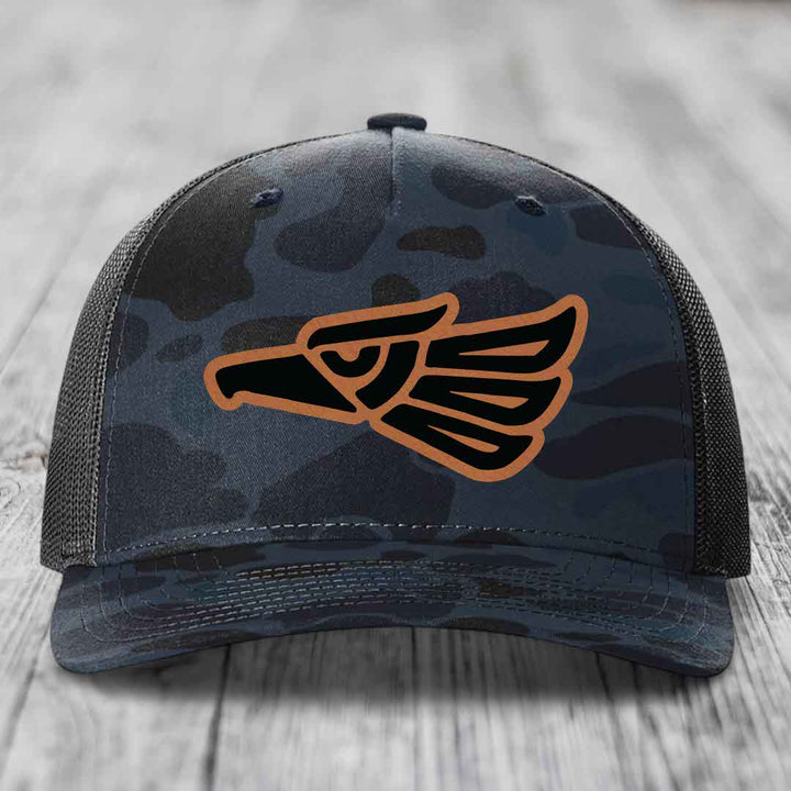 Camouflage trucker hat with Aztec eagle patch in black and tan.