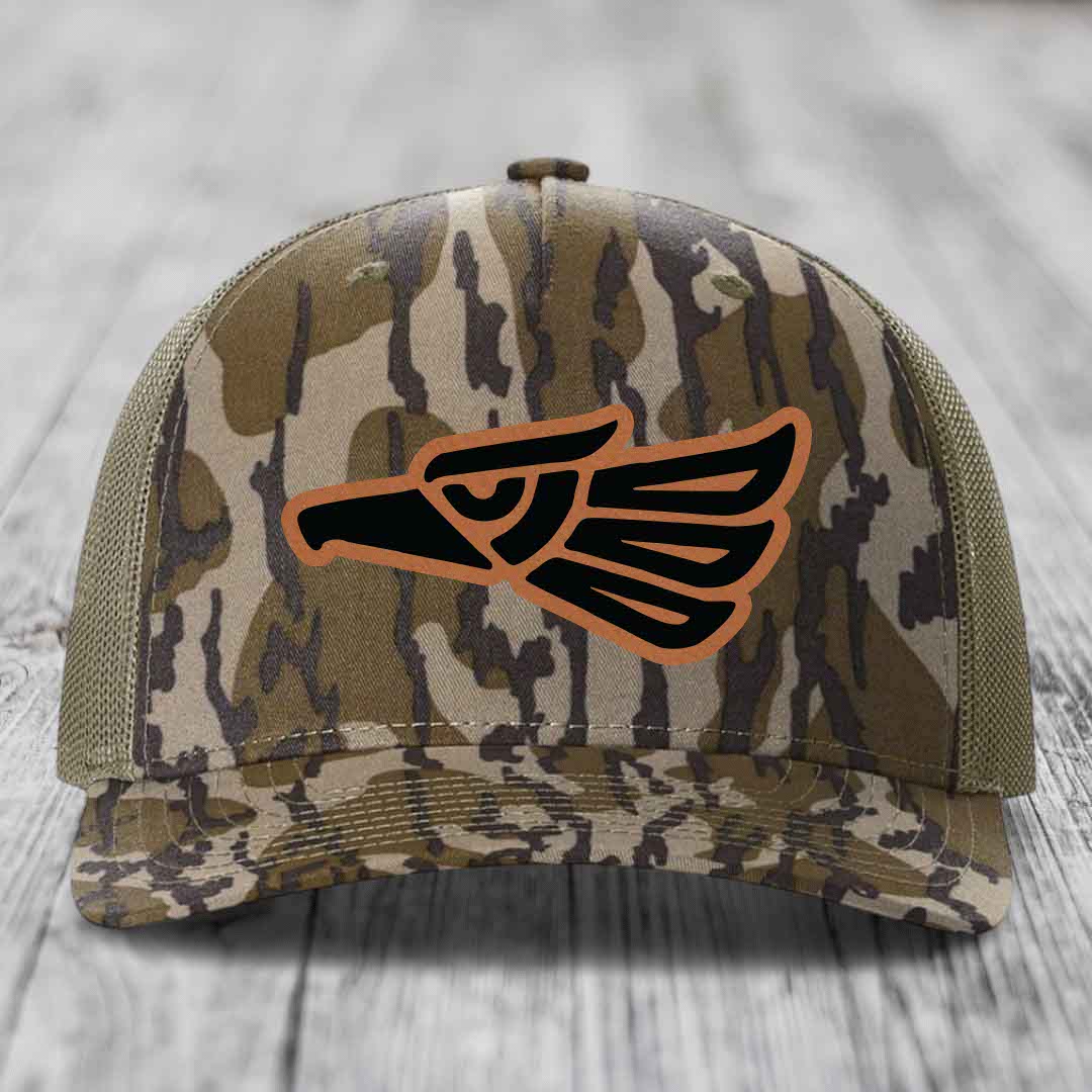 Camouflage trucker hat with black and brown eagle patch on front.