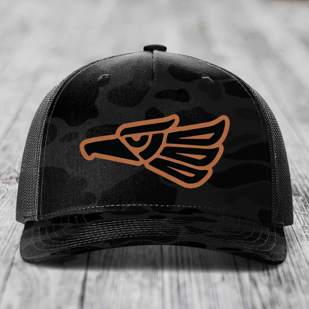 Black camouflage trucker hat with brown Aztec eagle patch on front.