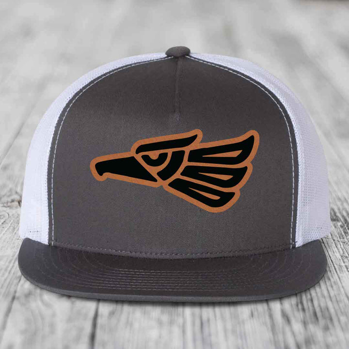 Grey front panel trucker hat with brown and black Aztec eagle patch.