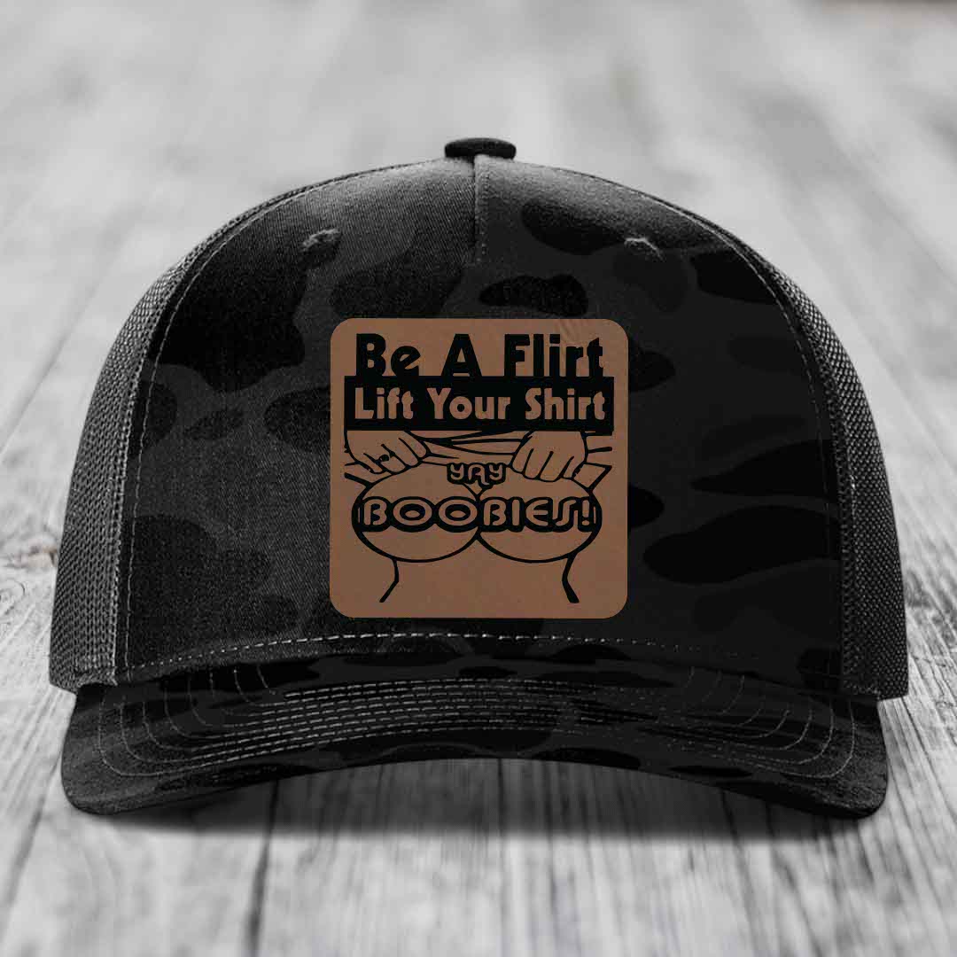 Black camouflage trucker hat with a brown leatherette patch reading &