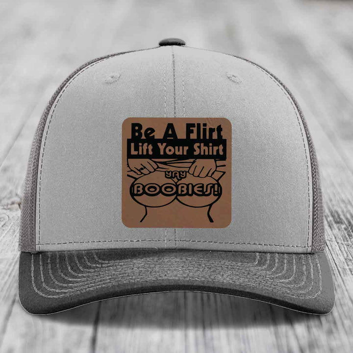 Grey trucker hat with brown leather patch reading &