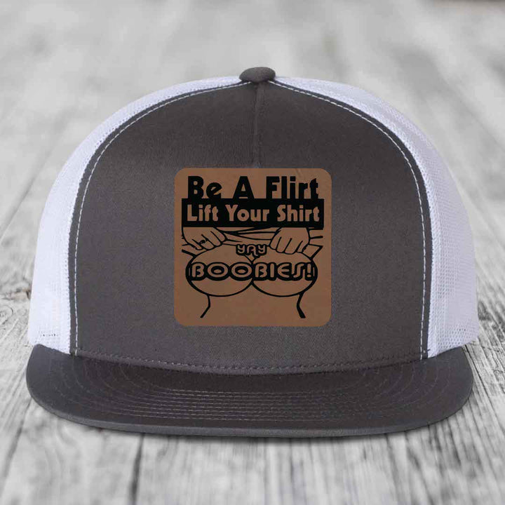 Grey and white trucker hat with brown leather patch reading &