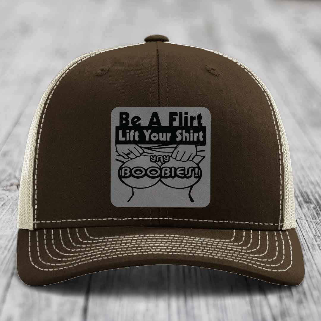 Brown trucker hat with white stitching and a gray patch reading &