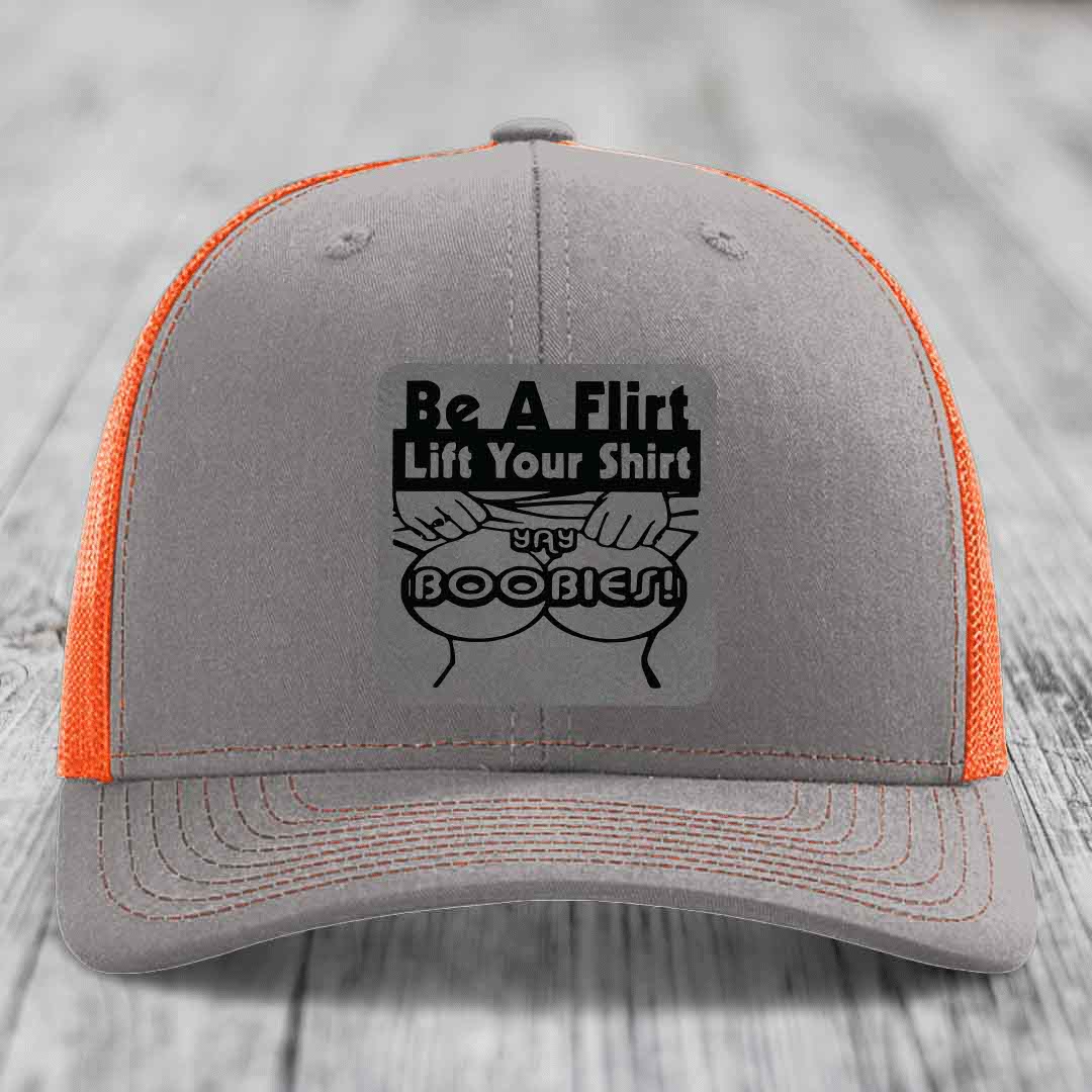 Grey trucker hat with orange mesh back and black patch reading &