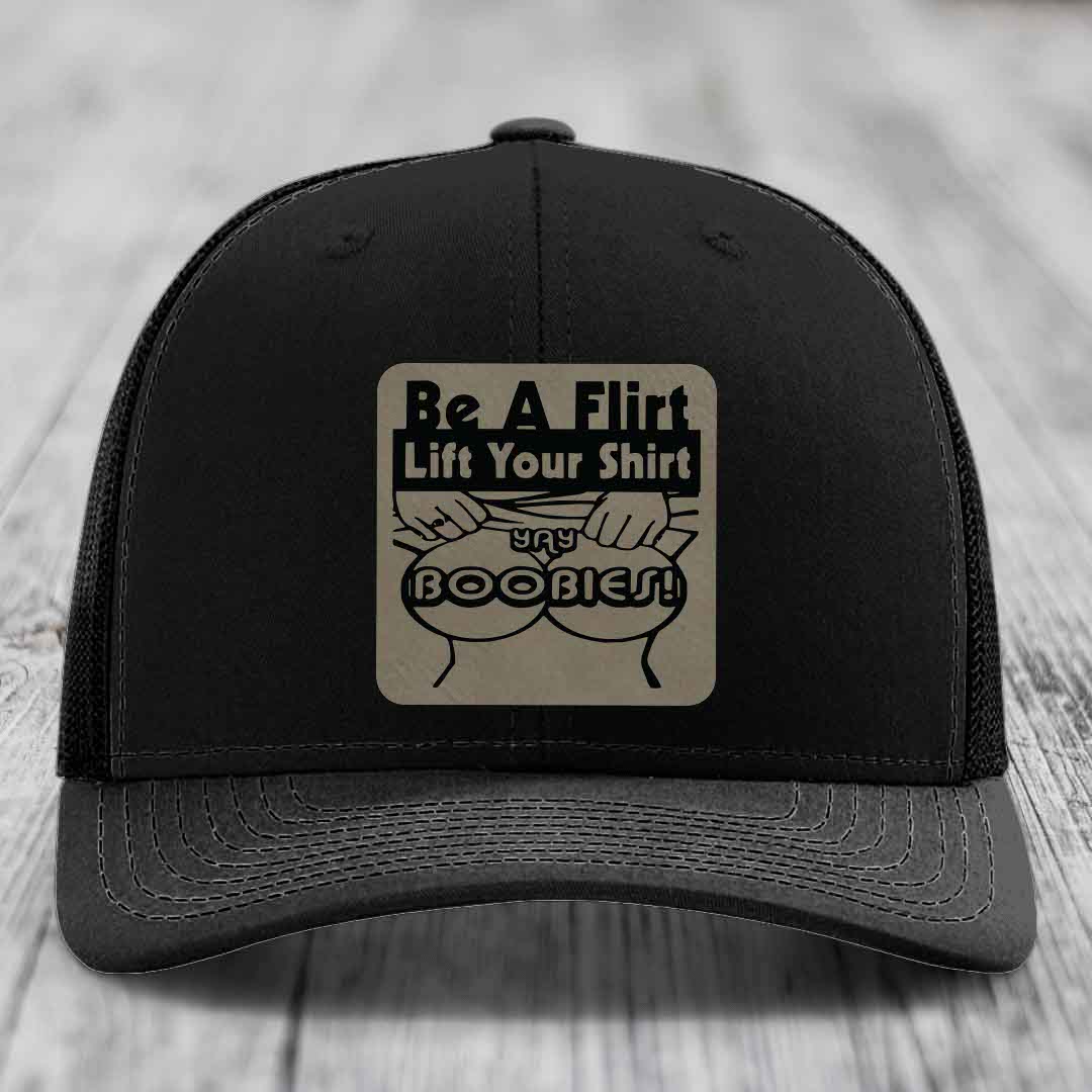 Black trucker hat with a beige leatherette patch reading &