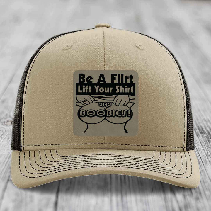 Tan trucker hat with black mesh back and a rectangular patch that reads &
