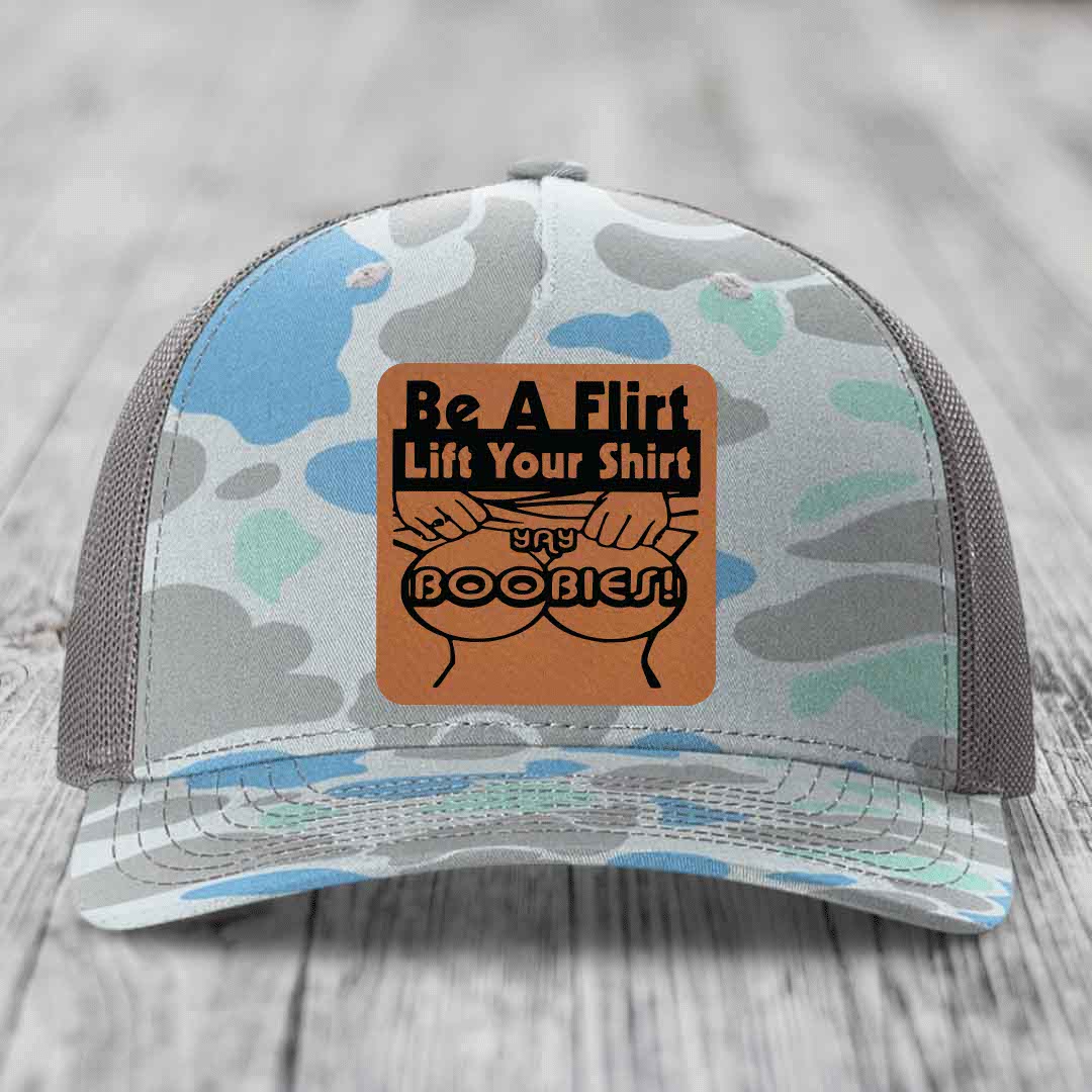 Camouflage trucker hat with brown leather patch reading &
