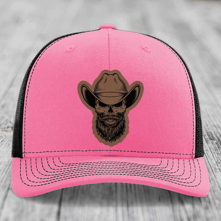 Pink trucker hat with black mesh back and a bearded cowboy skull patch on front.