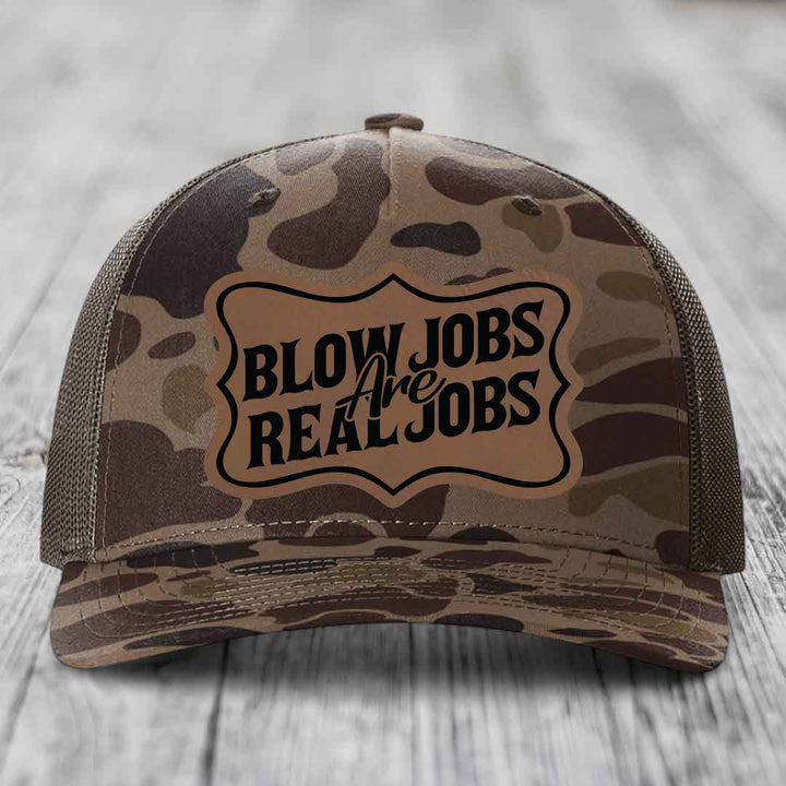 Camouflage trucker hat with a brown leatherette patch that reads &