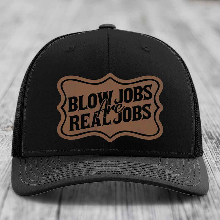 Black trucker hat with brown leatherette patch reading &
