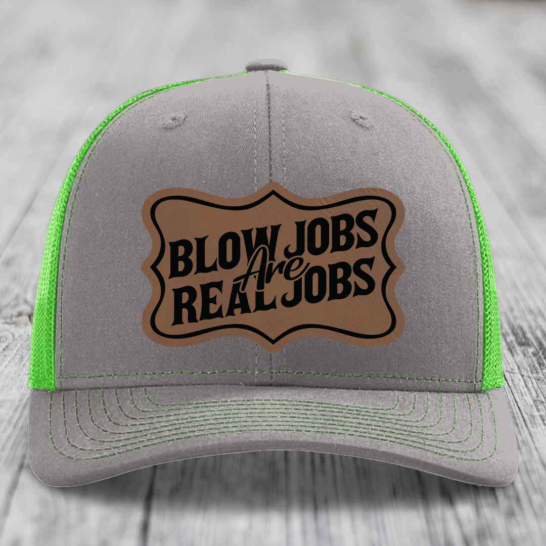 Grey trucker hat with neon green mesh and stitching, featuring a brown leatherette patch that reads &