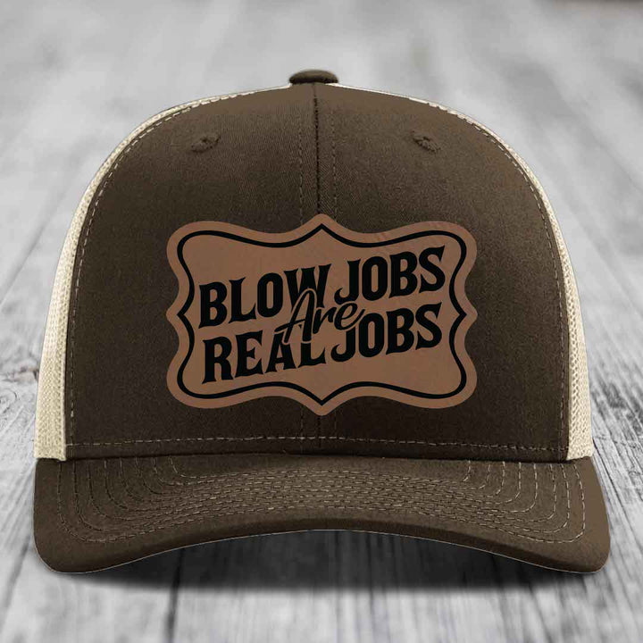 Brown trucker hat with beige mesh back and a brown leatherette patch that reads &