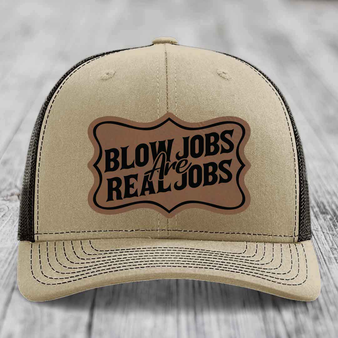 Beige trucker hat with black mesh back and a brown leatherette patch reading &