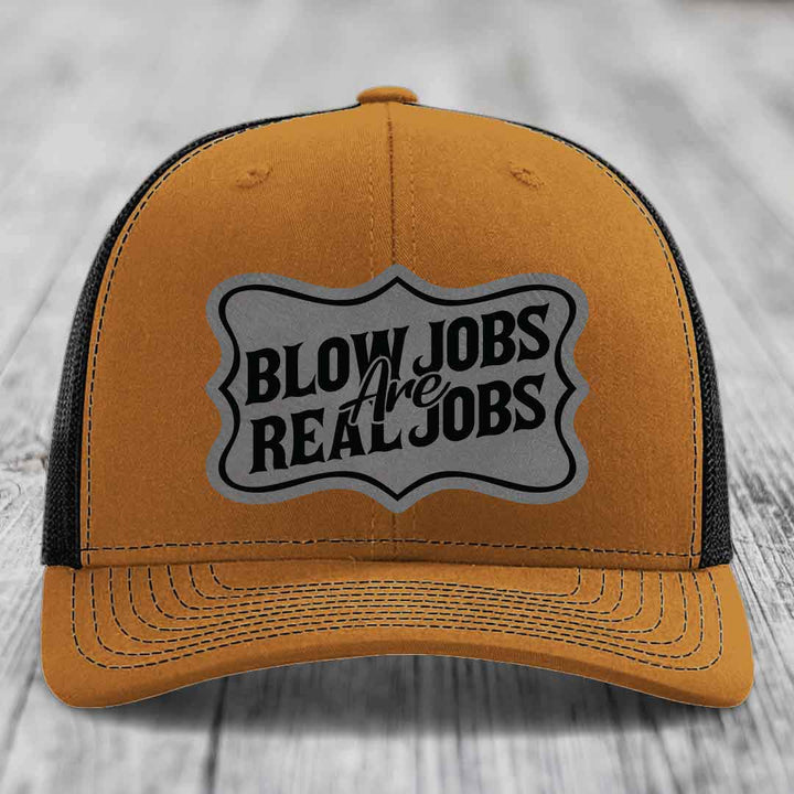 Tan trucker hat with black mesh back and gray patch reading &