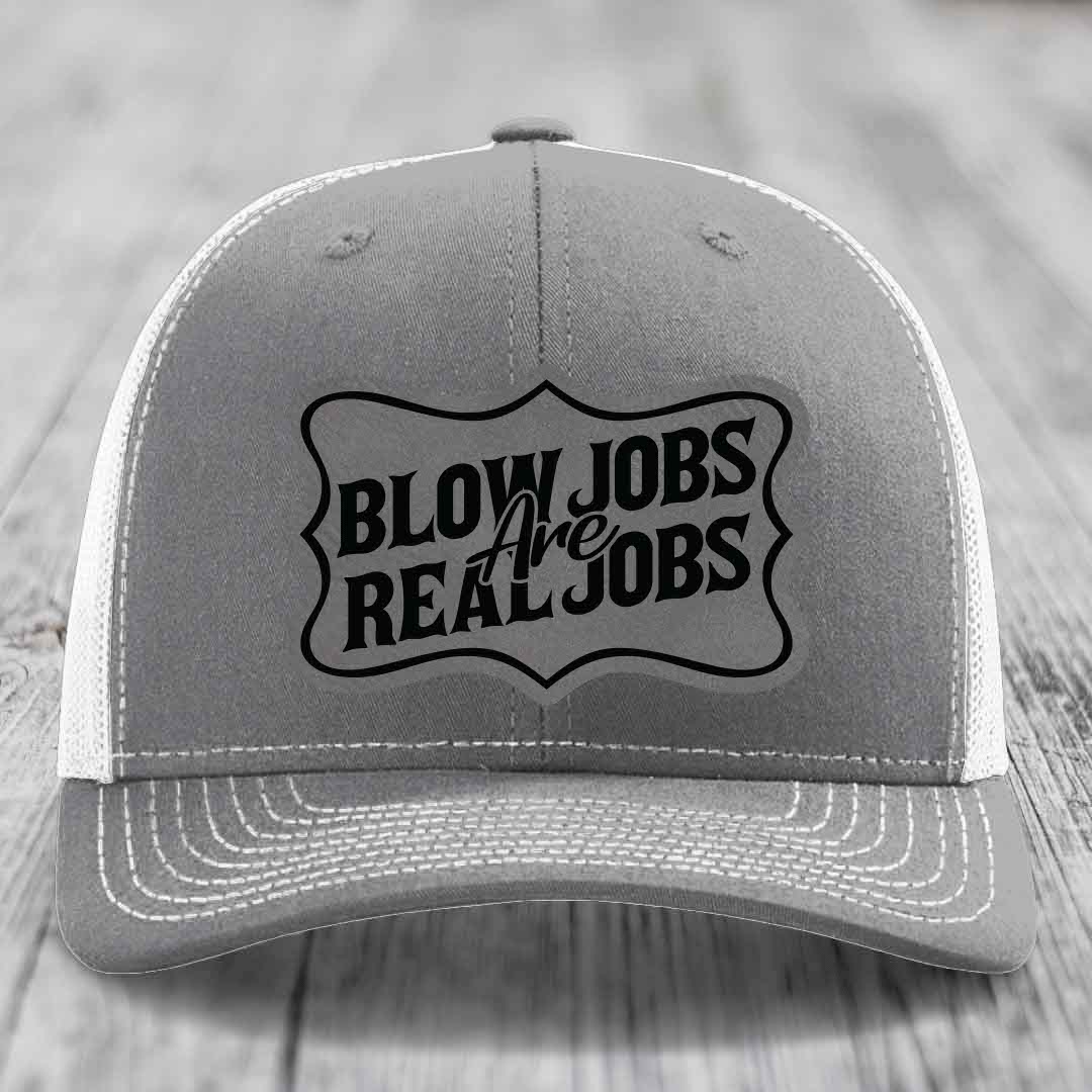 Grey trucker hat with black embroidered patch reading &