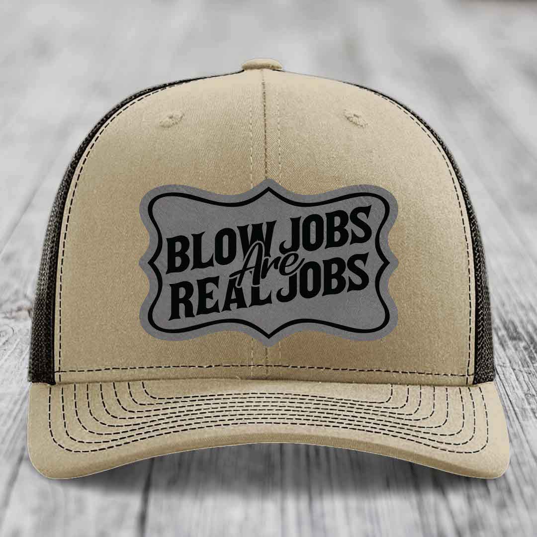 Tan trucker hat with black mesh back and a grey shield patch that reads &