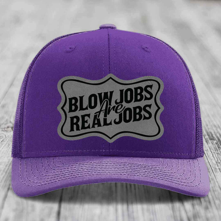 Purple trucker hat with a grey shield patch that reads &