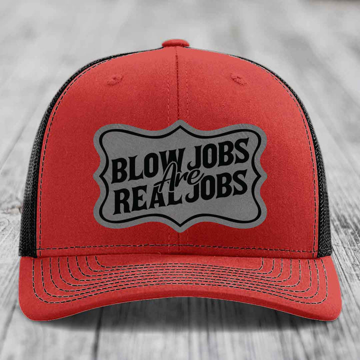 Red trucker hat with black mesh back and gray patch reading &