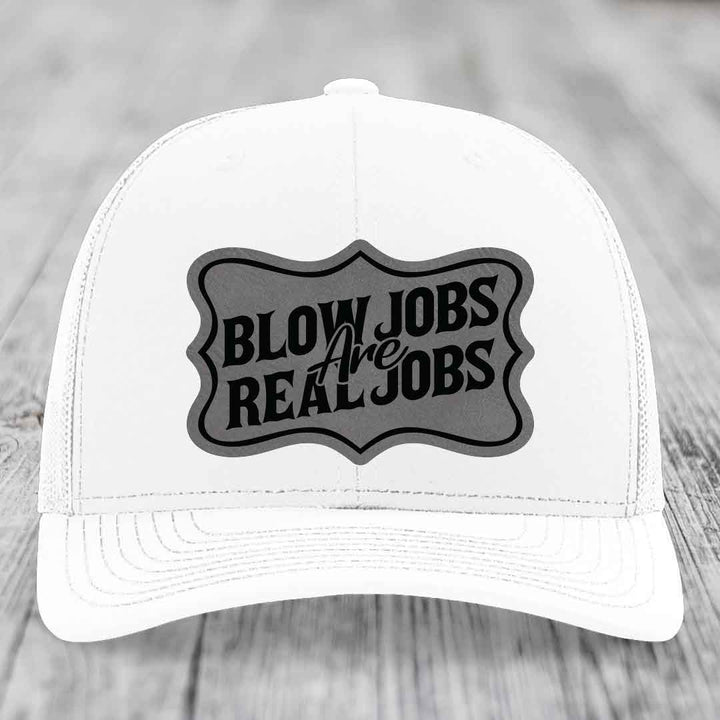 White trucker hat with black and grey patch reading &