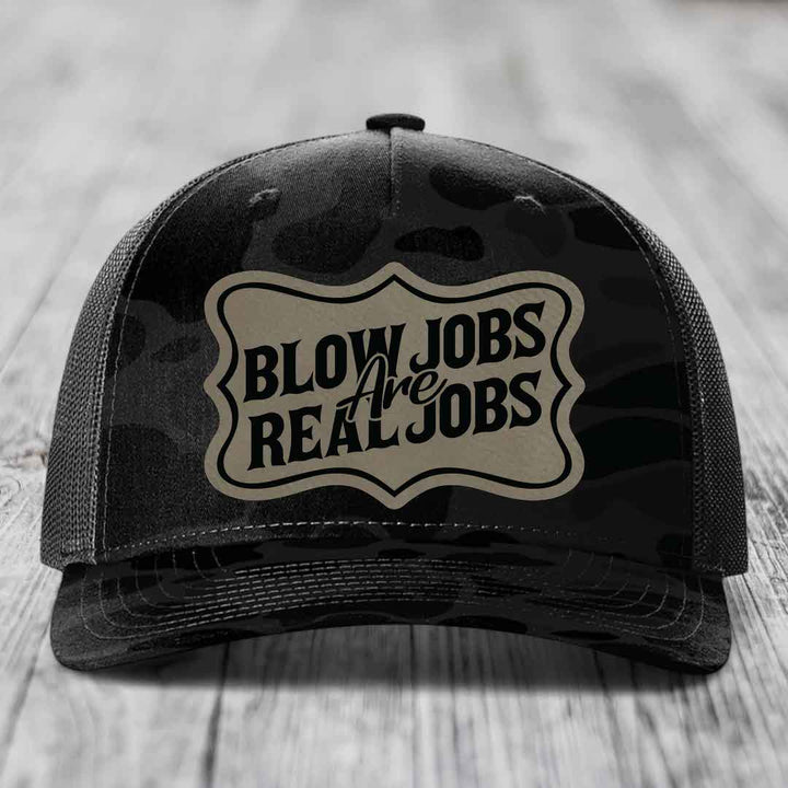 Black trucker hat with camouflage pattern and a beige patch that reads &