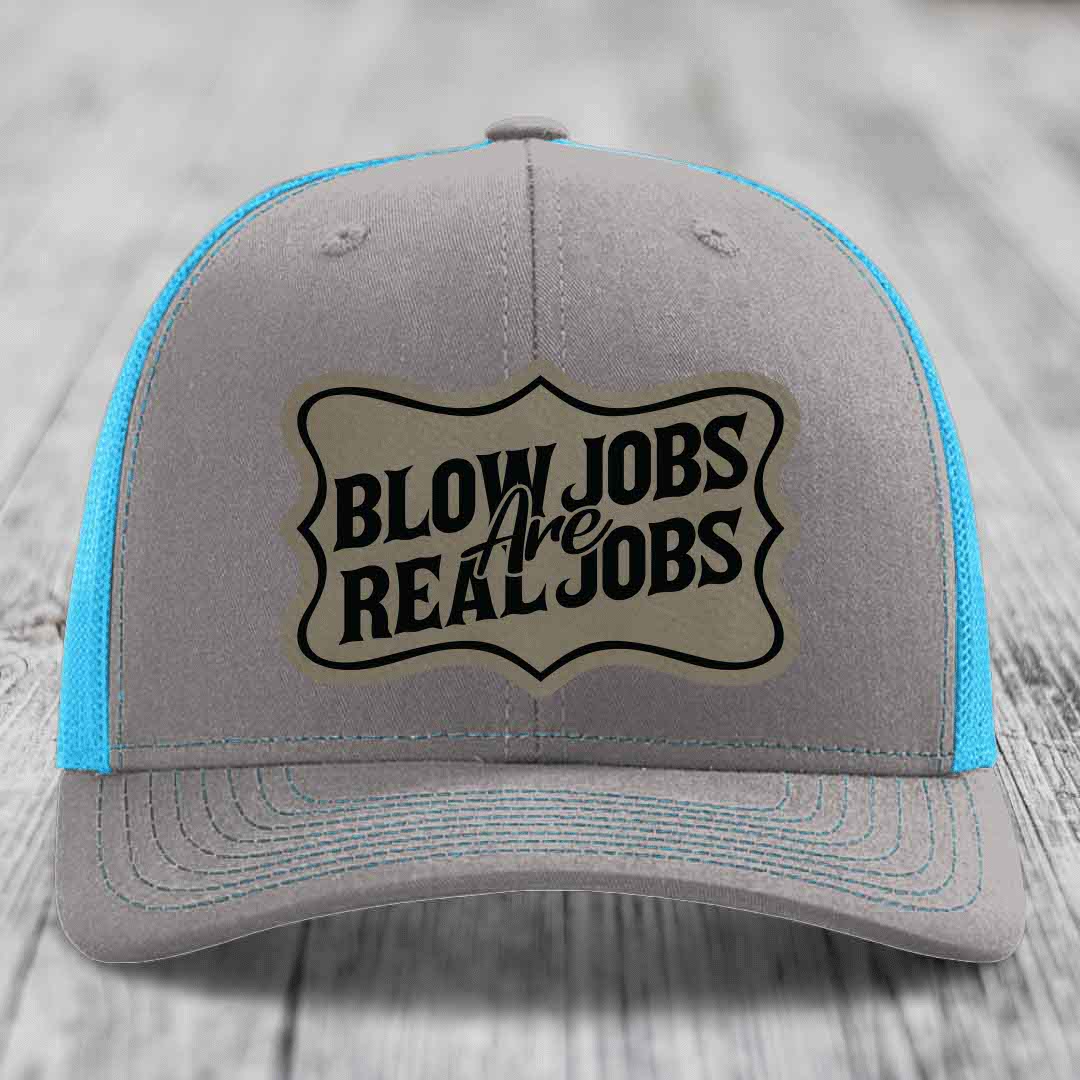Grey trucker hat with blue mesh sides and a beige leatherette patch reading &