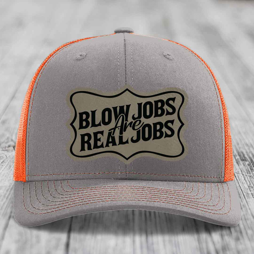Grey trucker hat with orange mesh back and black embroidered patch reading &