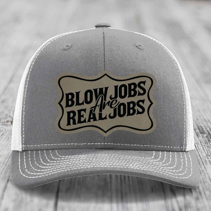 Grey trucker hat with white mesh back and embroidered patch reading &