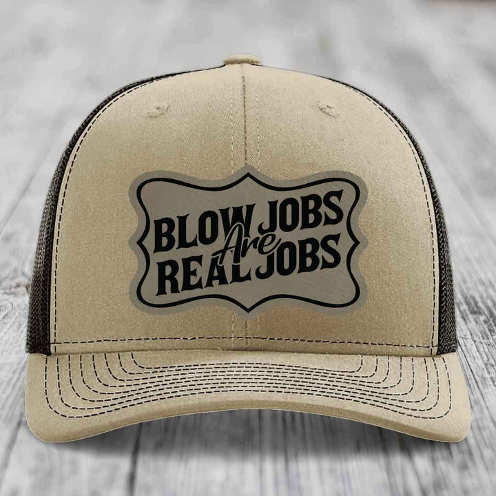 Tan trucker hat with black mesh back and embroidered &
