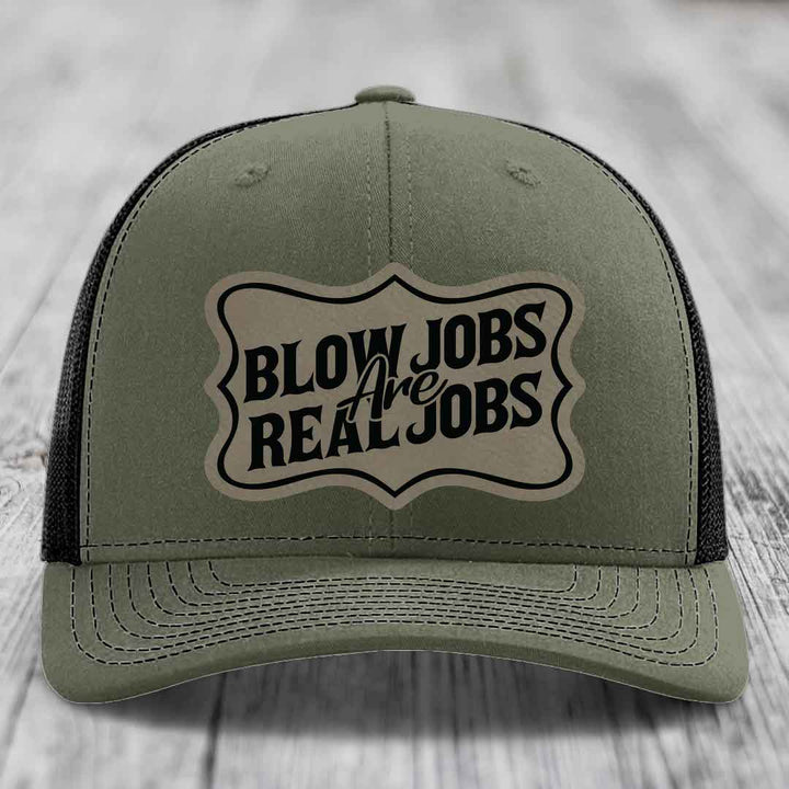 Olive green trucker hat with black mesh back and a beige leatherette patch reading &