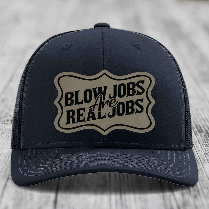 Dark blue trucker hat with beige leatherette patch reading &