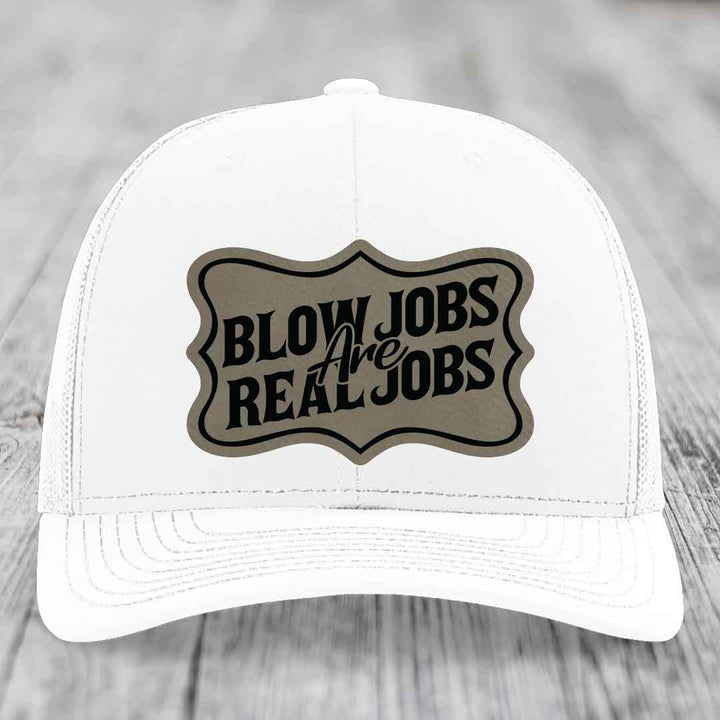 White trucker hat with a brown leatherette patch that reads &